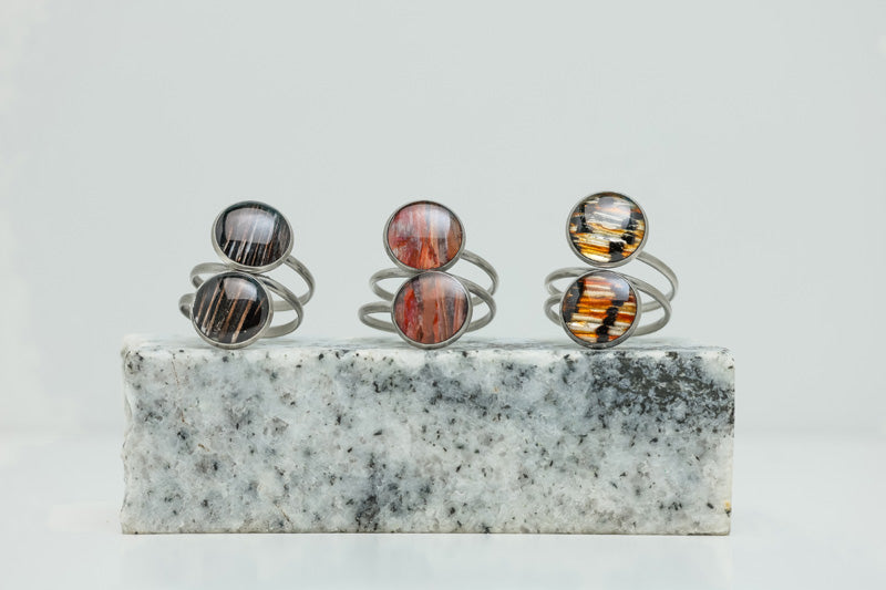Three Silver Double Pendant Statement Rings on black and white marble on a white background.