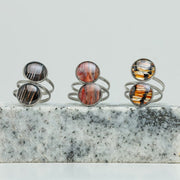 Three Silver Double Pendant Statement Rings on black and white marble on a white background.