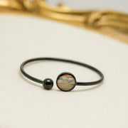 A Black Cuff on a white background with a gold frame. 