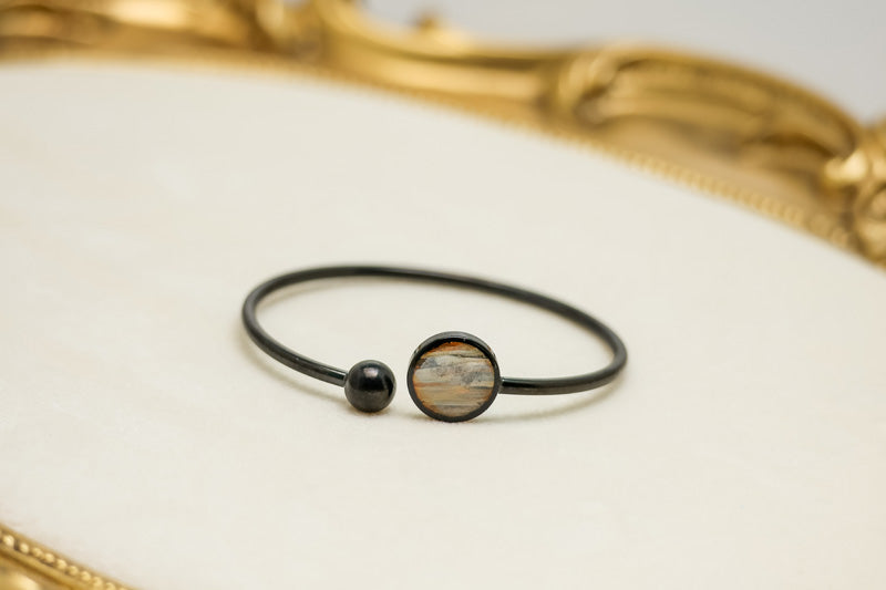 A Black Cuff on a white background with a gold frame. 