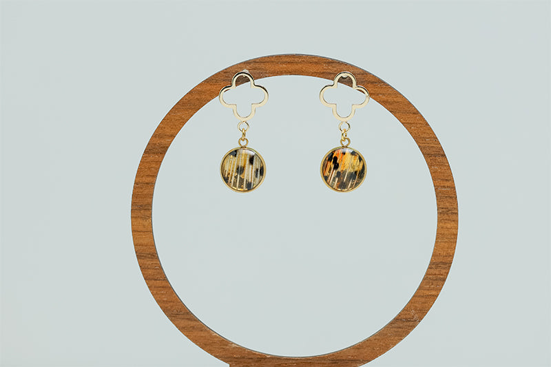 A pair of Four Leaf Clover Earrings on a circular wooden stand on a white background. 