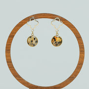 A pair of Four Leaf Clover Earrings on a circular wooden stand on a white background. 