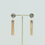 Golden Tassel Earrings on a gold stand on a white background.