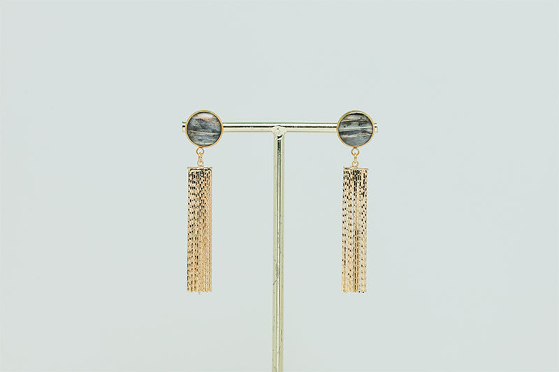 Golden Tassel Earrings on a gold stand on a white background.