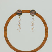 Cascading Diamond Earrings on a circular wooden stand on a white background.  