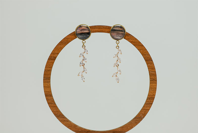 Cascading Diamond Earrings on a circular wooden stand on a white background.  