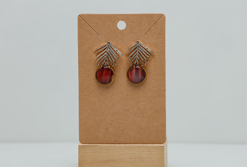 Golden Palm Earrings on a cardboard stand on a white background.