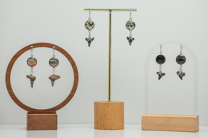 Three Shark Tooth Silver Dangle pairs on stands on a white background. 