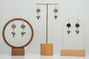 Three Shark Tooth Silver Dangle pairs on stands on a white background. 