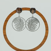 Tropical Palm Earrings on a circular wooden stand on a white background.