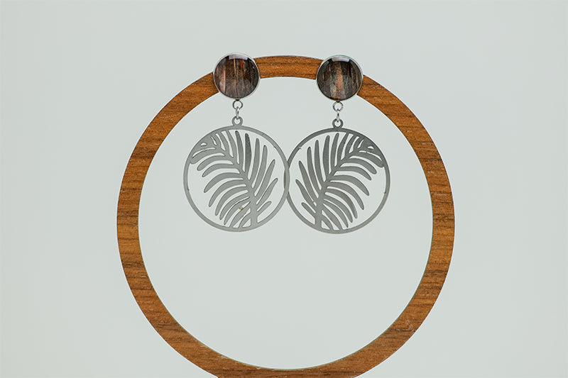 Tropical Palm Earrings on a circular wooden stand on a white background.