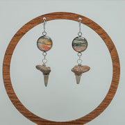 Shark Tooth Silver Dangle on a wooden circular stand on a white background. 