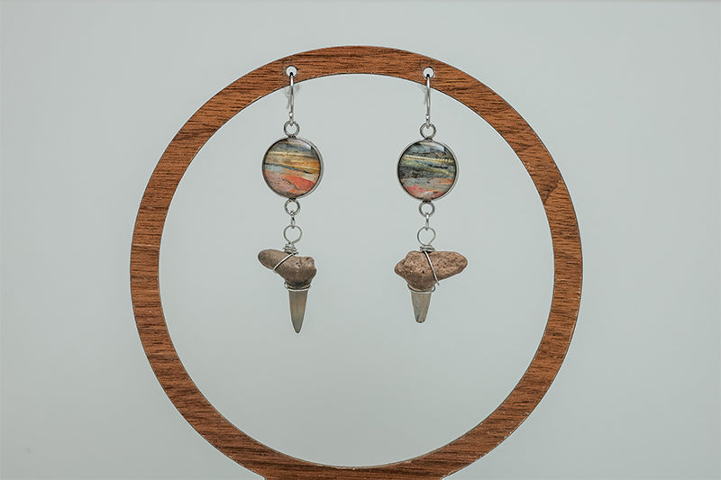 Shark Tooth Silver Dangle on a wooden circular stand on a white background. 