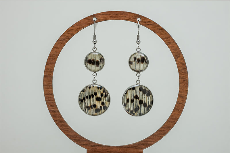 Dual Lionfish Silver Dangles on a circular wooden stand on a white background.  