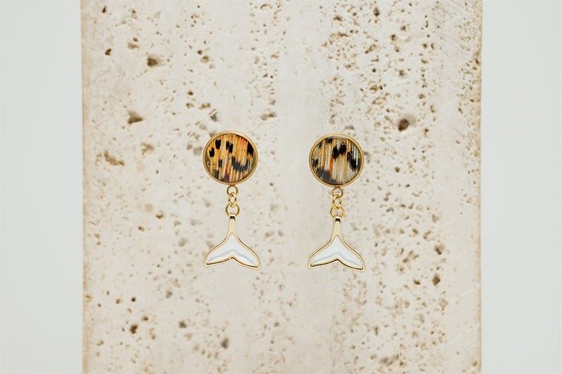  A pair of Freshwater Pearl Whale Tail Earrings on white marble on a white background.