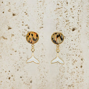  A pair of Freshwater Pearl Whale Tail Earrings on white marble on a white background.