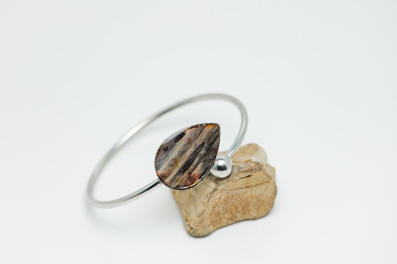 Silver Teardrop Cuff on a rock on a white background. 
