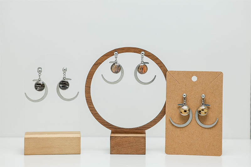 Three pairs of Silver Moons Earrings on stands on a white background.  
