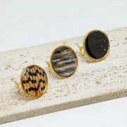 Three Gold Statement Rings on white marble on a white background.