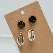 Cowrie Shell Posts on a cardboard stands on a white background with white coral.