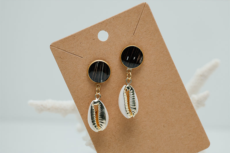 Cowrie Shell Posts on a cardboard stands on a white background with white coral.