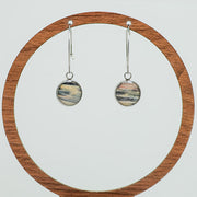 Silver Hoops on a circular wooden stand on a white background. 
