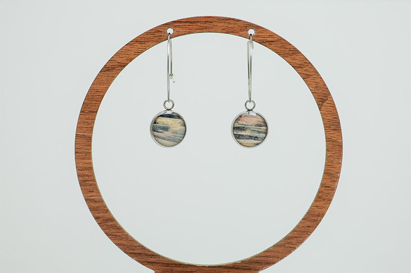 Silver Hoops on a circular wooden stand on a white background. 