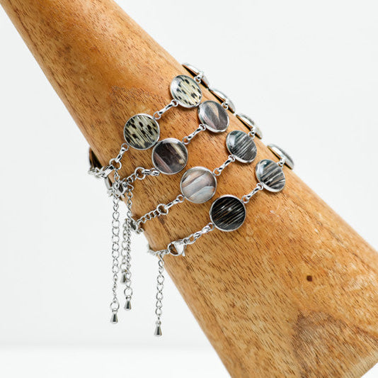 Four Silver Tennis Bracelets on a wooden triangle on a white background. 