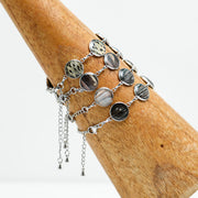 Four Silver Tennis Bracelets on a wooden triangle on a white background. 