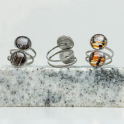 Three Silver Double Pendant Statement Rings on black and white marble on a white background.