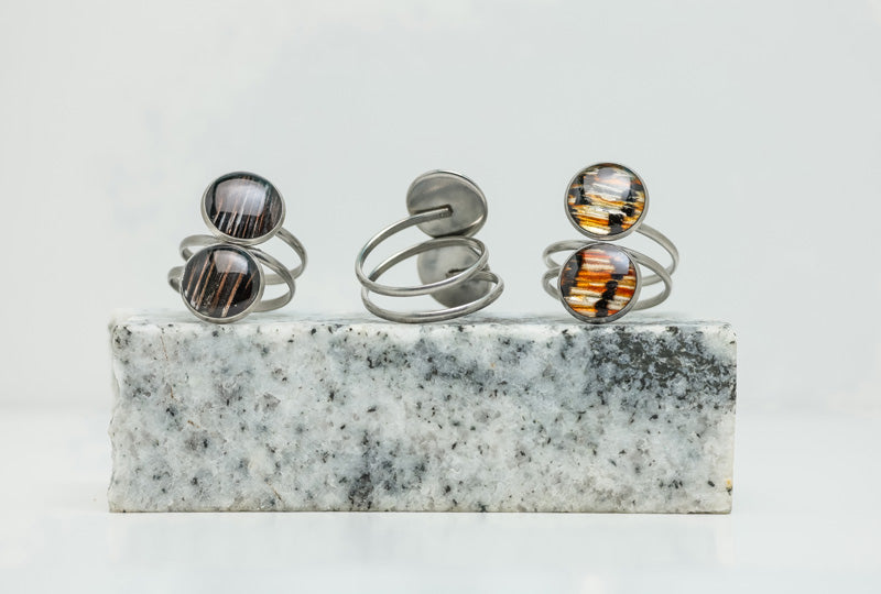 Three Silver Double Pendant Statement Rings on black and white marble on a white background.