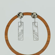 Surf + Shine Earrings on a circular wooden stand on a white background.  