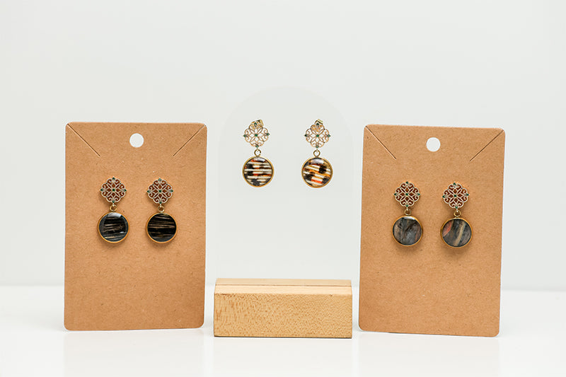 Three Gold Enchanted Emerald Earrings  on a white background. Two pairs are displayed on cardboard stands.