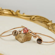 Three Rose Gold Cuffs on a rock on a white background with gold frame.