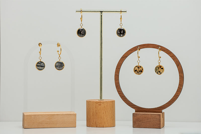 Three pairs of Gold Open Hoop Posts on stands on a white background. 