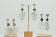 Three pairs of Monstera Leaf Mandala Drops on stands on a white background. 
