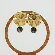 Bold Golden Disc Earrings on a circular wooden stand on a white background.  