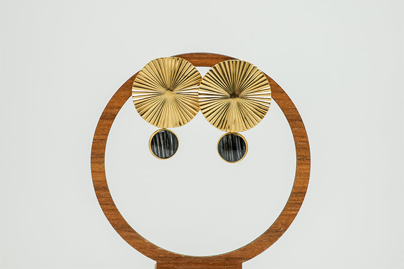 Bold Golden Disc Earrings on a circular wooden stand on a white background.  