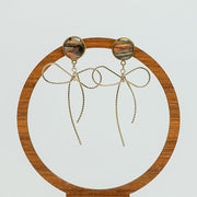 Bows Before Bros Earrings on a circular wooden stand on a white background.  