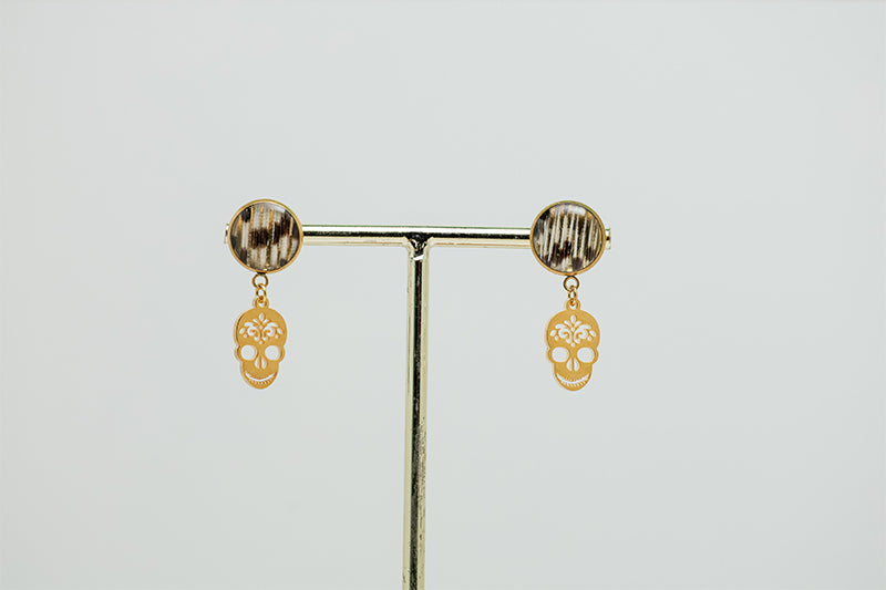 A pair of Sugar Skull Earrings on a gold stand on a white background.