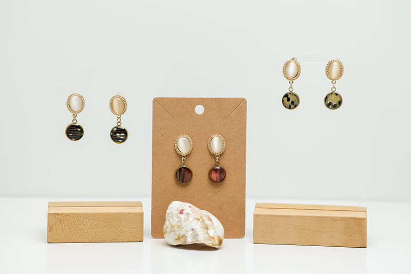 Three pairs of Freshwater Pearl Earrings on a white background with a shell at the bottom of the image.