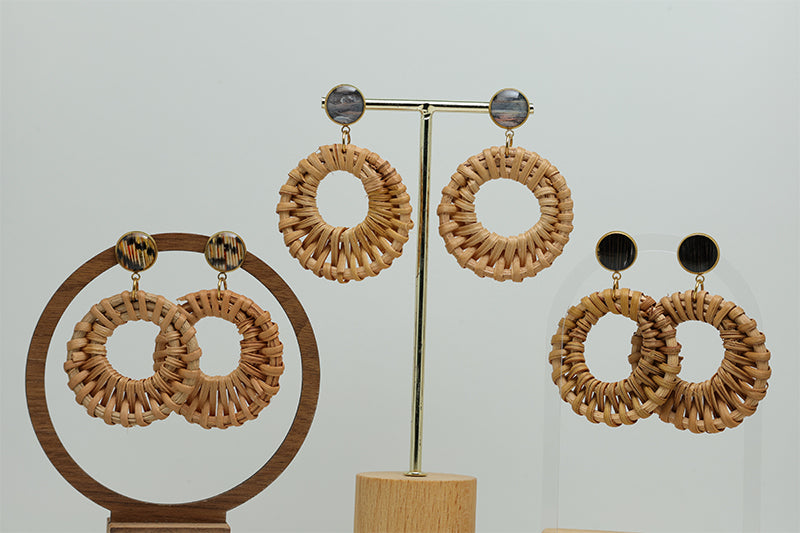 Three pairs of Boho Rattan Hoop Earrings on stands on a white background.  