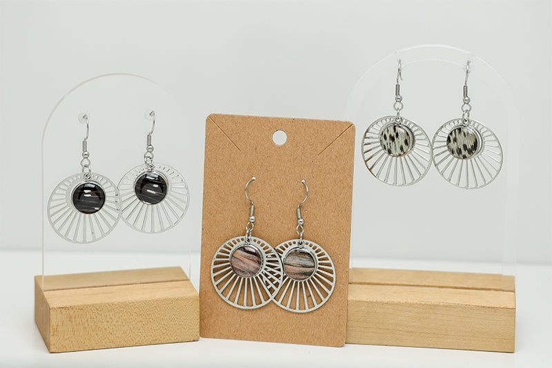 Three pairs of Sun Rays Earrings on stands on a white background.  