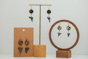 Three Shark Tooth Gold Dangles Earrings on stands on a white background. 