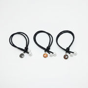 Three black hair ties with two pearls and a lionfish charm on each on a white background.