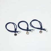 Three blue hair ties with two pearls and a lionfish charm on each on a white background.