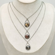 Three Teardrop Necklaces on a cream necklace display bust. 