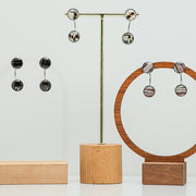 Three pairs of  Ear Jacket Post Earrings on stands on a white background. 