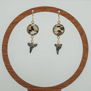 Shark Tooth Gold Dangles Earrings on a circular wooden stand on a white background. 