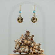 Blue Lagoon Opal Earrings on a white background with a shell at the bottom of the image. 